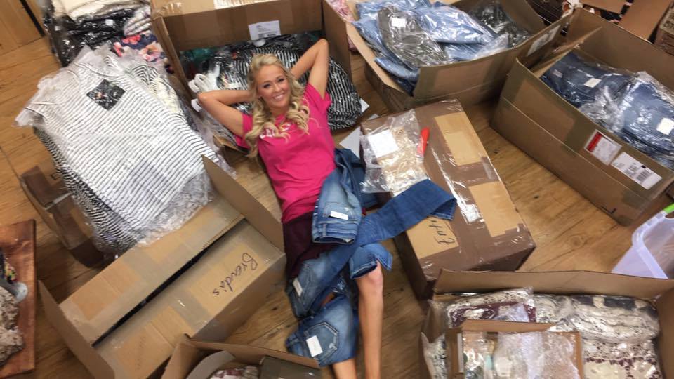 A photo of one of the Pulse Boutique founders laying on boxes of products.