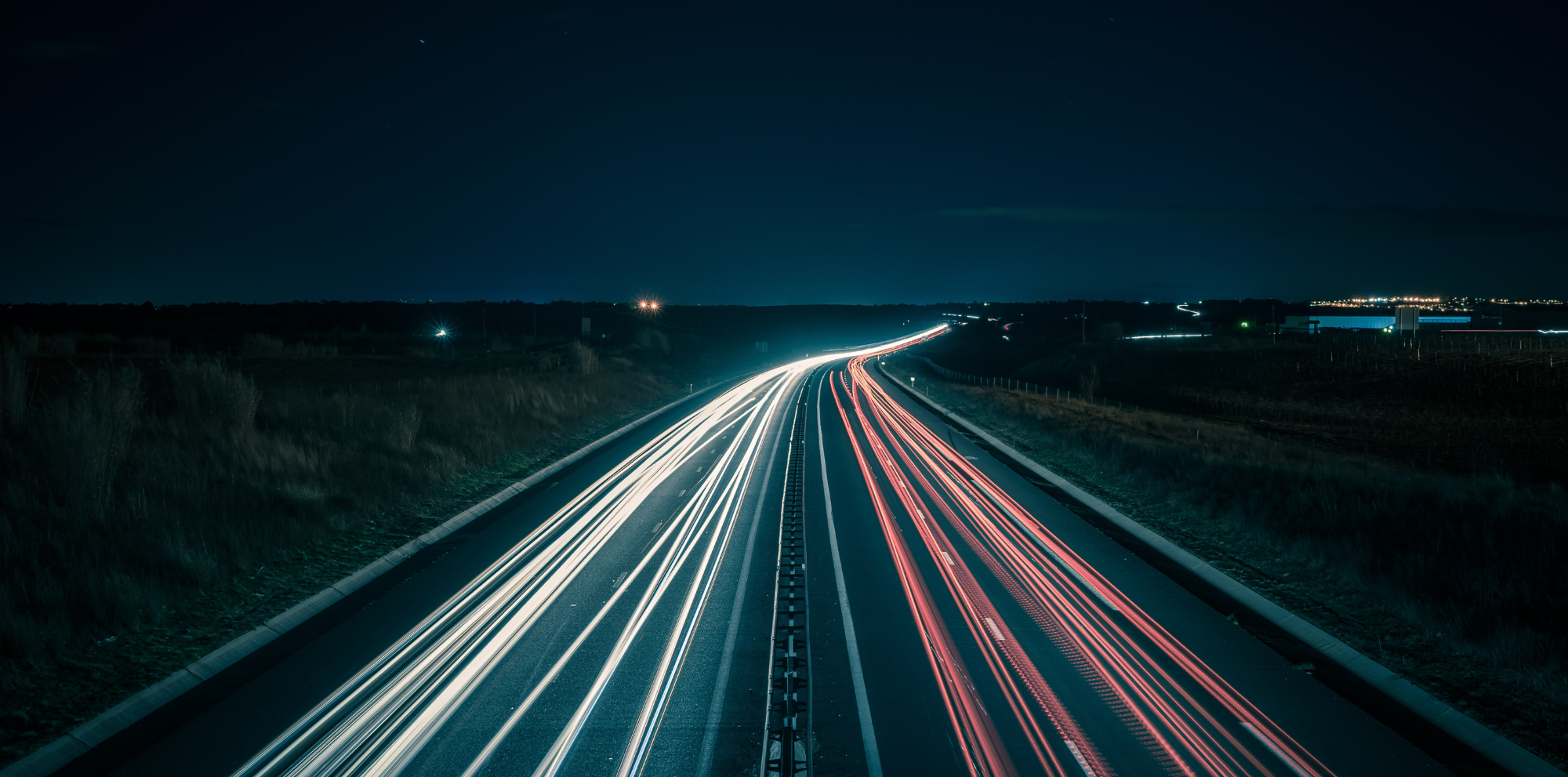 Slow shutter speed image of road at night; car lights streaming in lines to represent Shopify site speed