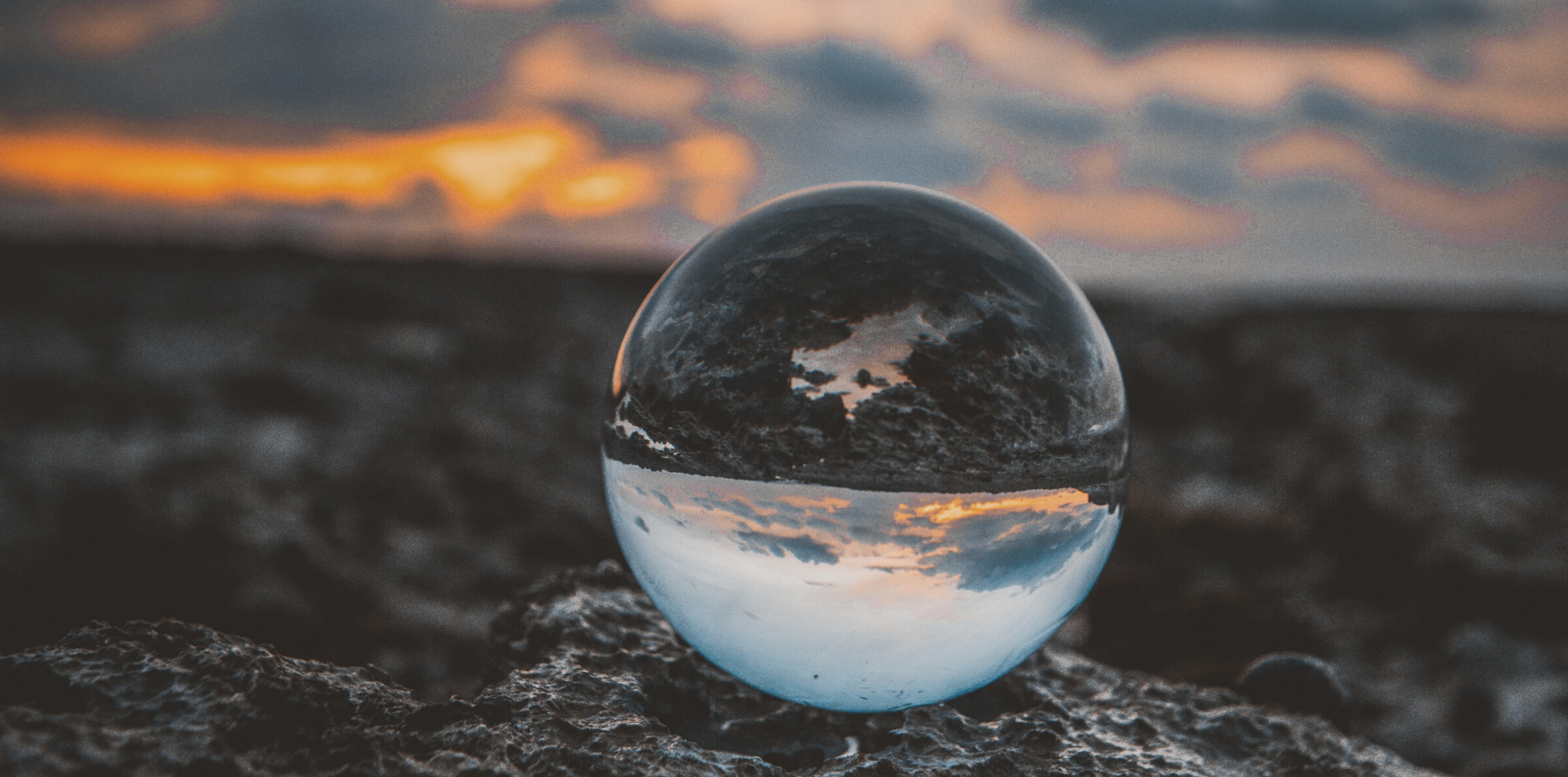 Glass ball with inverted image of coast line and sunset; representing website discovery process.